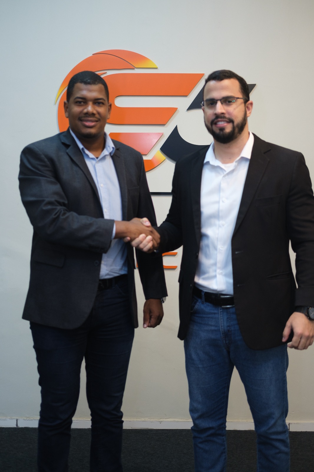 Representantes da Solar Cavalcante cumprimentando-se em frente à logo da empresa